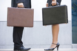 Man and woman, facing each other and each carrying a briefcase.