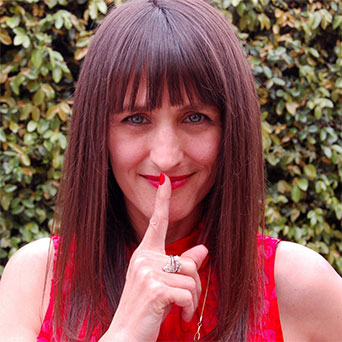 Photo of Gretchen Hydo with finger at her lips showing the Shhhh gesture