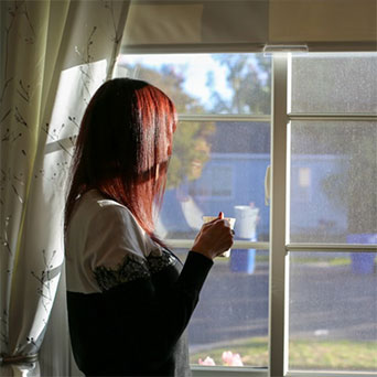Photo of woman looking thoughtfully out a window