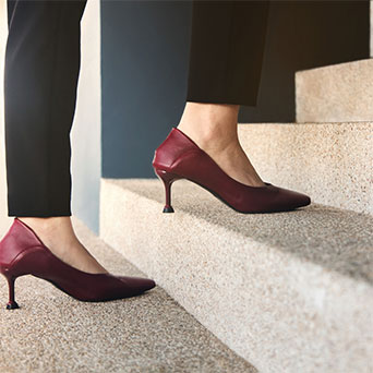 Photo of woman's feet in high heels and business attire walking up steps.