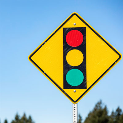 yellow road sign indicating a stoplight ahead.